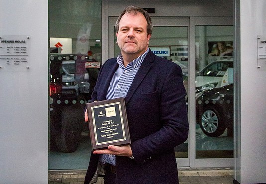 Dominic Threlfall of Pebley beach with a plaque commemorating 25 years as a Suzuki dealer